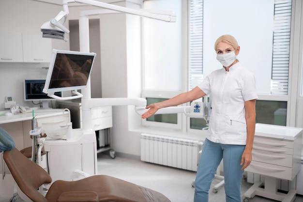 Dentist showing her patient where to sit in her office