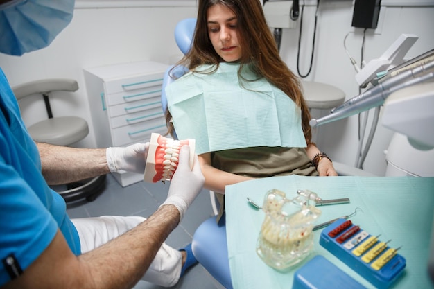 Dentista che mostra la tecnica di pulizia dei denti al cliente.