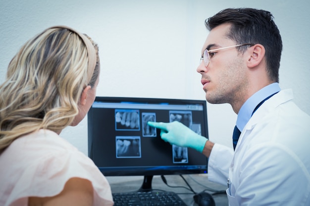 Foto dentista che mostra a donna i suoi raggi x della bocca sul computer