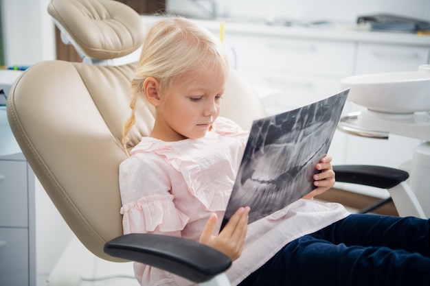 Dentist shows a little patient an x-ray of her teeth