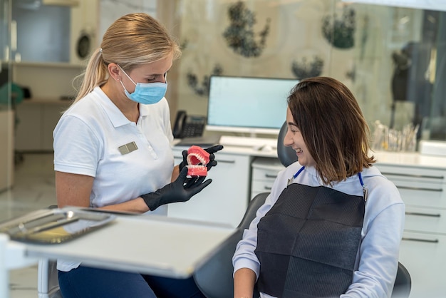 Dentist shows on model of the jaw how to properly brush the teeth with a toothbrush