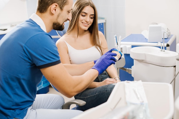 A dentist shows patient ceramic model of teeth and explain to her about work