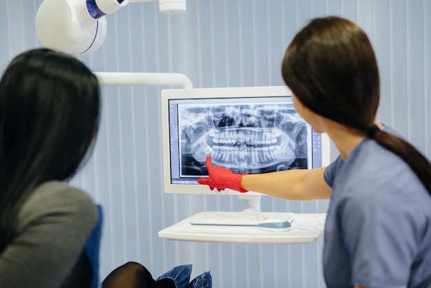 The dentist shows a picture of the patient's teeth and tells the necessary treatment. Dentistry, health.