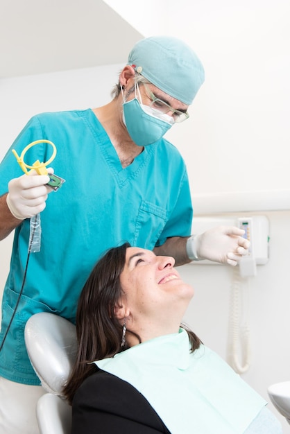 Dentist and smiling patient looking each other while puting an xray tool