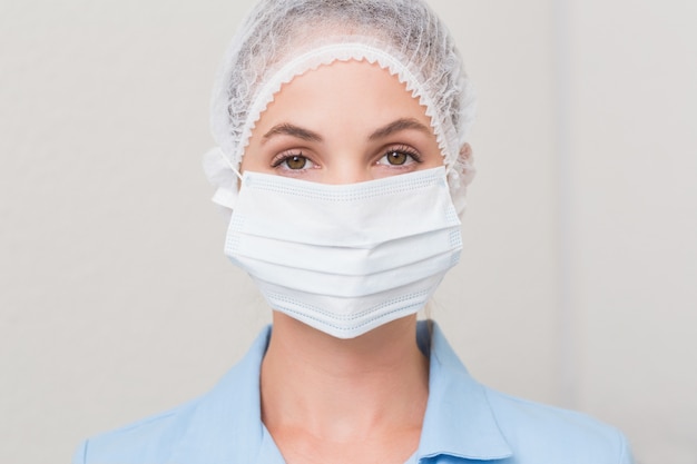 Dentist in surgical mask and cap looking at camera