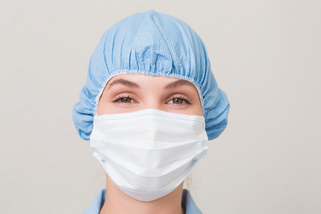 Dentist in surgical mask and cap looking at camera