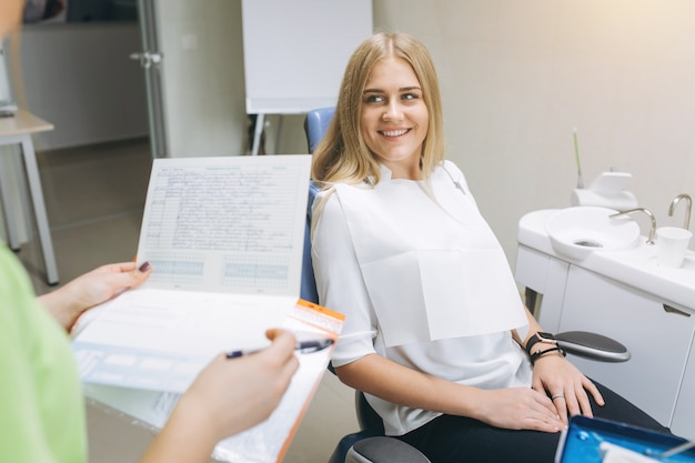 Il dentista insegna a una ragazza l'igiene orale sulle parentesi graffe in una clinica dentistica.