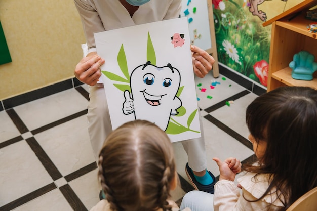 Il dentista dice ai bambini come lavarsi i denti. prevenzione della carie, odontoiatria pediatrica, concetto di igiene dei denti da latte