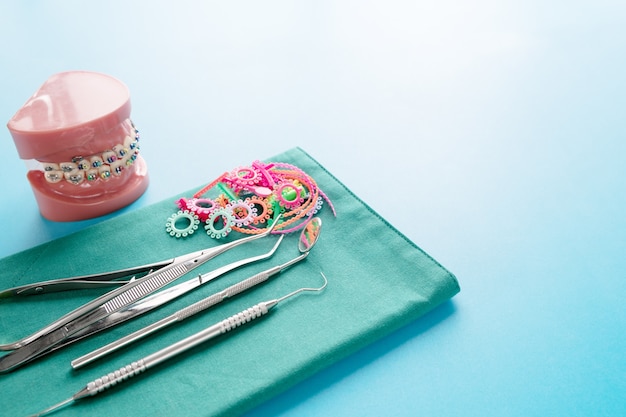 Dentist tools and orthodontic model on blue surface