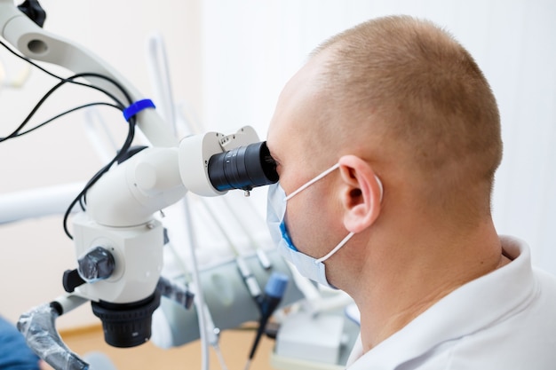 The dentist treats his patient's teeth with a microscope. The dentist treats the patient's mouth. Dental care. High quality photo