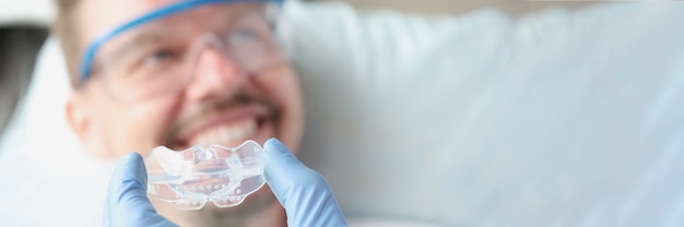 Dentist tries on silicone mouthguard to patient