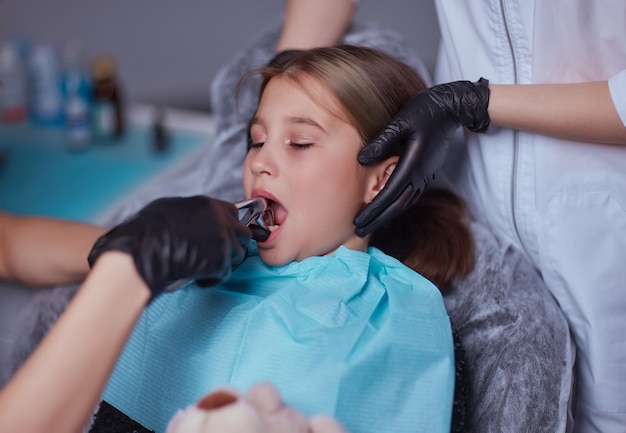 Стоматолог использует инъекцию анестетика для удаления зуба у ребенка.