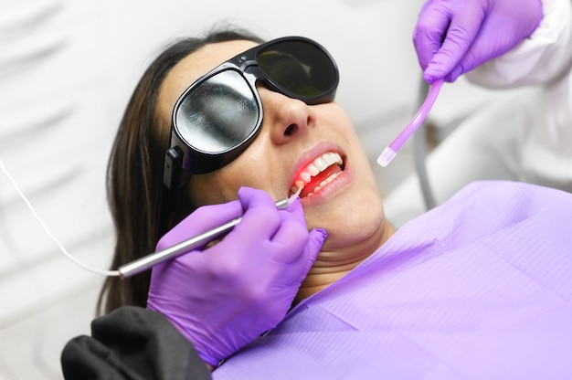 Стоматолог с помощью современного диодного стоматологического лазера.