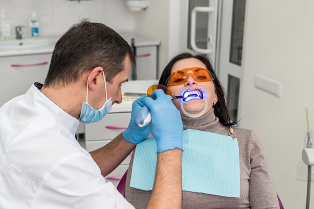 Dentist using uv lamp while treating patient's teeth