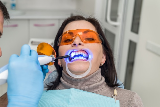 Dentist using uv lamp while treating patient's teeth