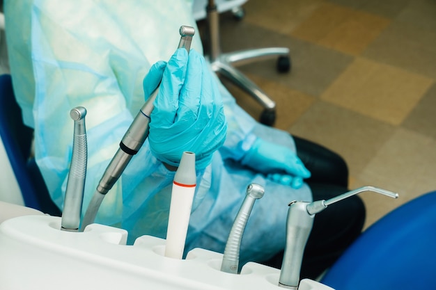 A dentist wearing gloves in the dental office holds a tool before working