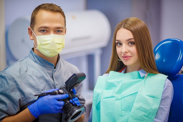 A dentist with a camera in his hands sits next to the patient. Portrait.