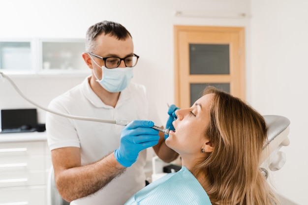 Dentist with dental drill treats woman in dentistry clinic Dental filling for girl patient