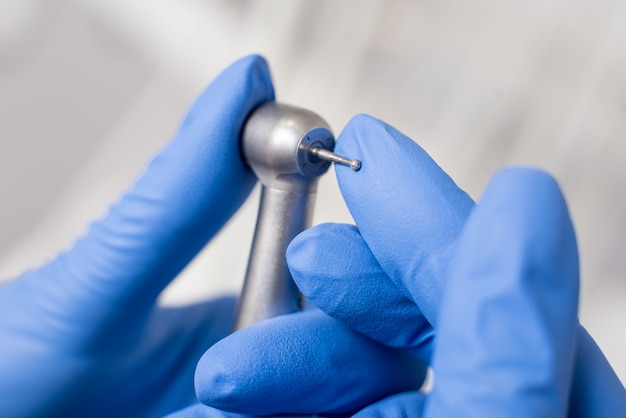 Dentist with gloved hands is working with dental equipment in dental office. Close-up