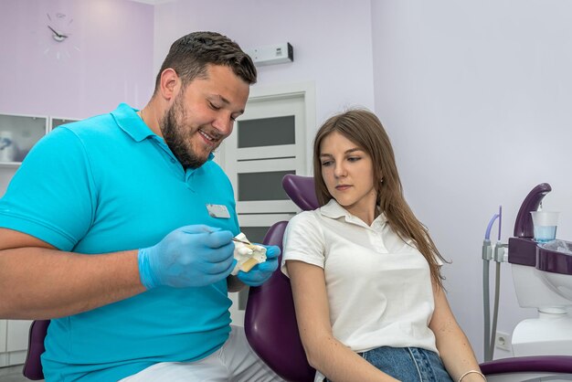 Dentist with hand pointing to xray image and talking to female patient about medication and surgical treatment dental health treatment of the oral cavity
