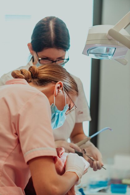 A dentist with the help of a colleague performs an operation on the jaw of an elderly patient in a modern dental clinic. High quality photo