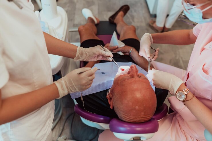 Photo a dentist with the help of a colleague performs an operation on the jaw of an elderly patient in a modern dental clinic. high quality photo