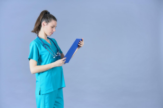 Dentist with stethoscope looking at medical report with aquamarine uniform on blue background