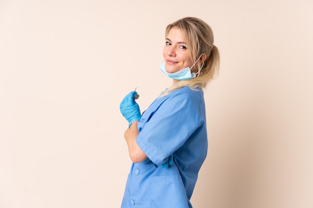 Dentist woman holding tools over isolated laughing