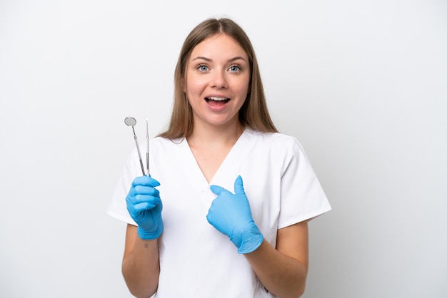 Dentist woman holding tools isolated on white background with surprise facial expression