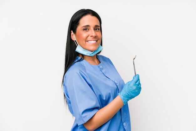 Dentist woman isolated on white wall looks aside smiling, cheerful and pleasant.