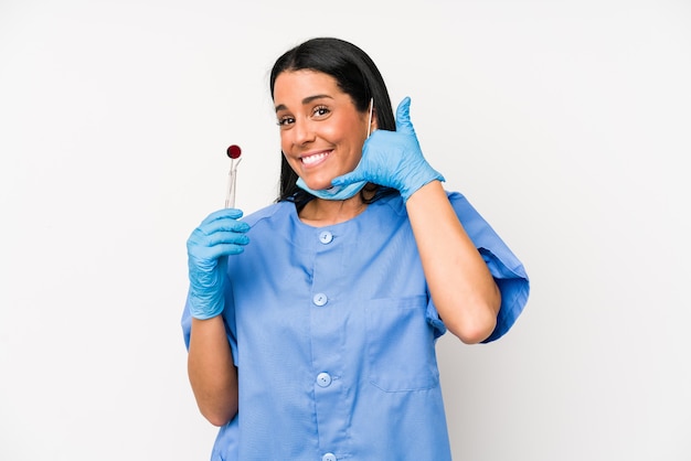 指で携帯電話の呼び出しジェスチャーを示す白い壁に隔離された歯科医の女性。