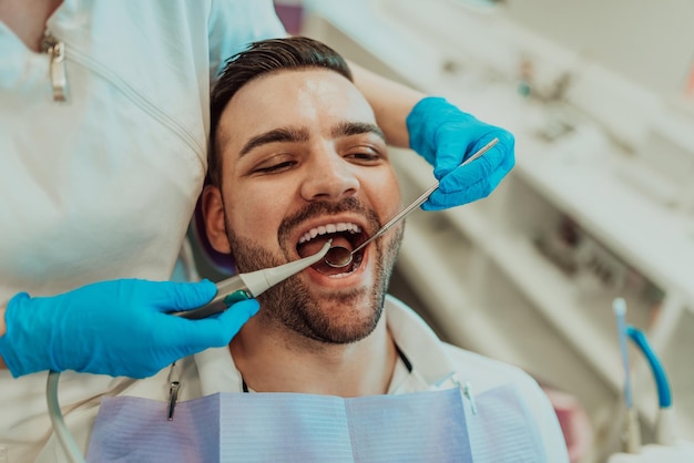 Dentist woman nurse checking patient mouth analyzing teeth infection using stomatological drill instrument during orthodontic examination in dental office room. Concept of dentistry procedure. High qu