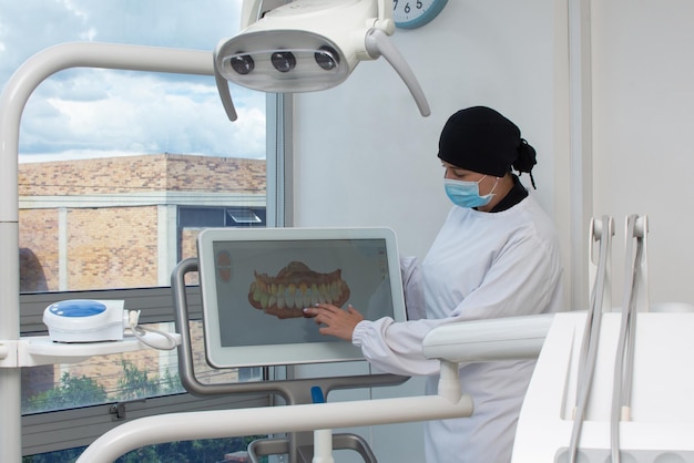 3D 歯科モデルを示す画面の横にある歯科医の女性 歯科医院のコンセプト
