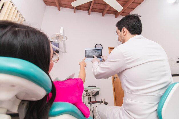 Foto dentista e giovane ragazza che puntano a una radiografia dentale nell'ufficio dentistico