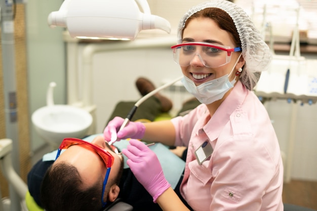 Стоматолог молодая женщина лечит пациента мужчина.
