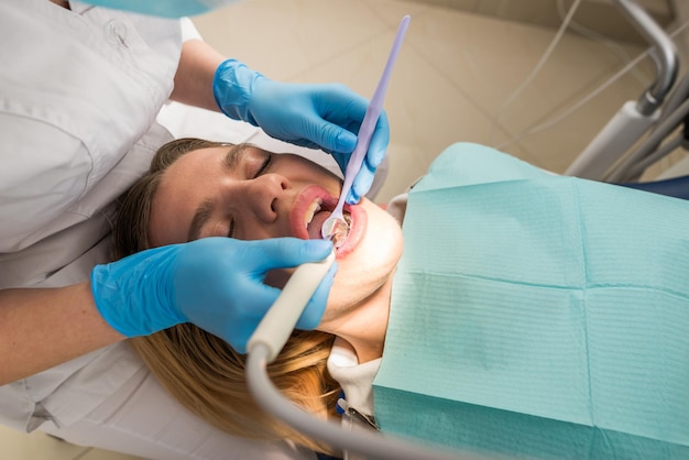 Foto il dentista conduce una procedura di pulizia dei denti per una ragazza in una clinica dentale rimozione del tartaro il concetto di trattamento dentale odontoiatrico