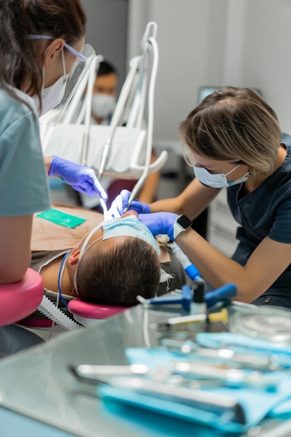 Foto odontoiatria in anestesia generale. il dentista cura il paziente in anestesia generale. dentista e assistente nel processo.