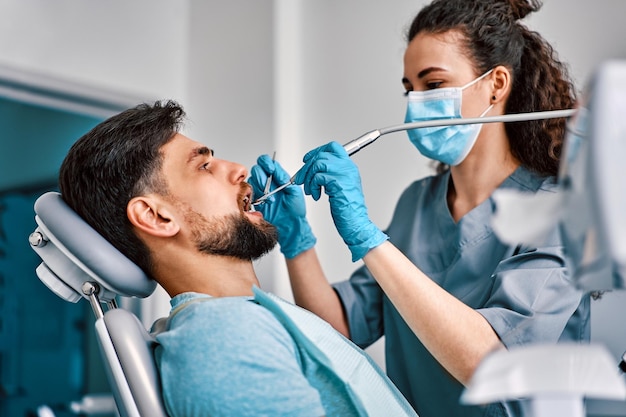 Foto medicina odontoiatrica una dentista donna con una maschera tratta i denti di un paziente