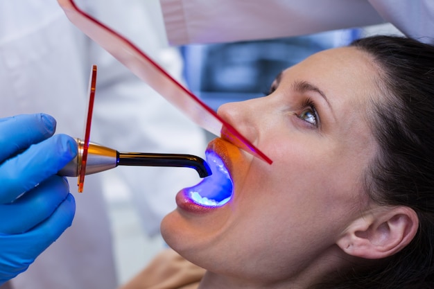 Dentists examining female patient with dental curing light