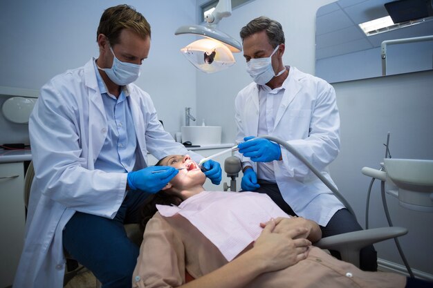 Dentists examining a female patient with tools