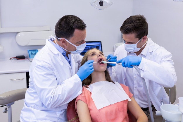 Dentists examining a male patient with tools