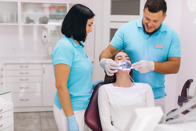 Dentists give the girl ultraviolet teeth whitening in a dental clinic