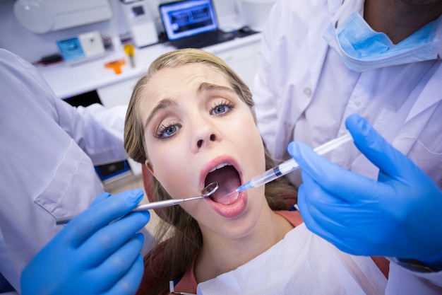 Dentists giving anesthesia to female patient