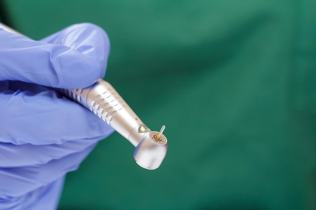 Dentists hand in a blue latex glove with new highspeed dental handpiece on blurred background