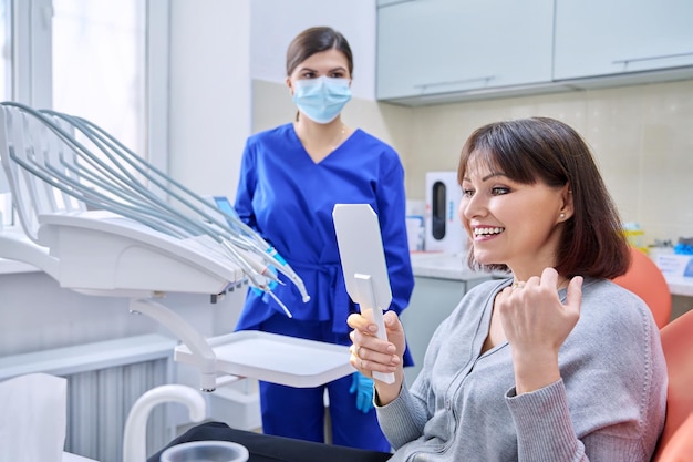 Dentists office woman patient looking at her teeth in the mirror