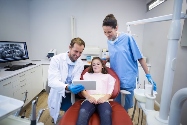 Dentisti che mostrano tavoletta digitale al giovane paziente