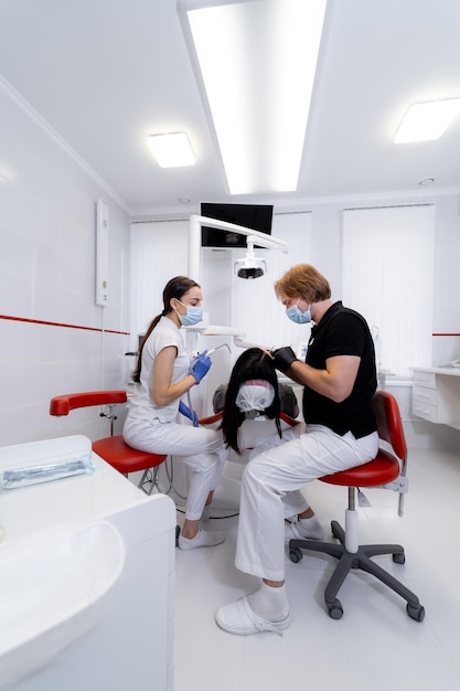 치과 의사는 환자의 치아를 치료합니다. 현대 치과 배경입니다. 건강 개념입니다. 의료진에 흰색 스크럽.