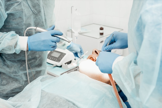 歯科医は手術、インプラント埋入を行います。実際の操作。抜歯、インプラント。プロの制服と歯科医の機器。ヘルスケア医師の職場を装備。歯科