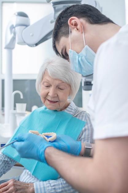 Denture. Male dental surgeon showing the denture to his npatient