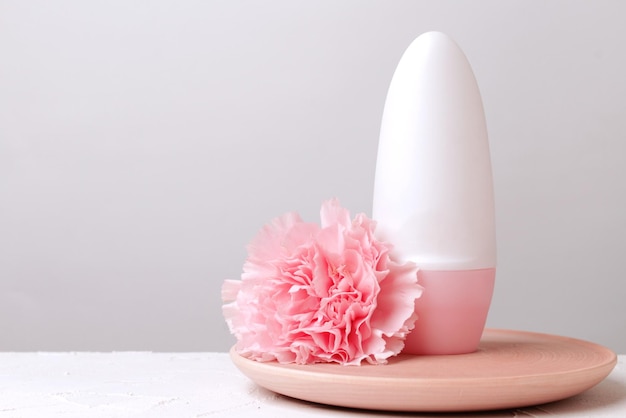 Deodorant and flower on pink background with copy space